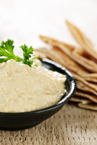 Bowl of fresh hummus dip with pita bread slices