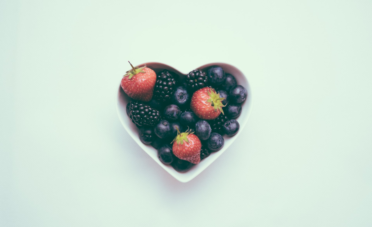 A heart-shaped bowl filled with strawberries and blueberries. High blood pressure is a major global health problem.
