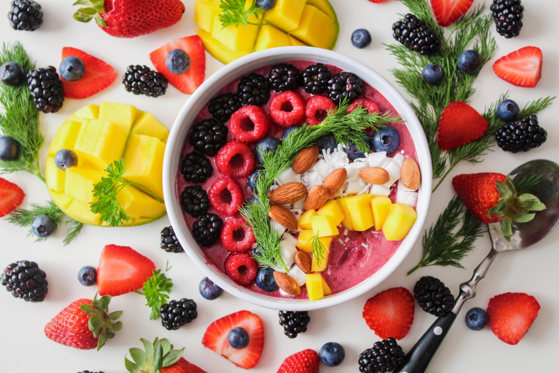 A Buddha bowl of fruit, veg and nuts accompanied by other vegan foods such as strawberries and mango