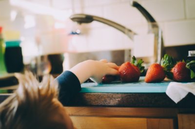 Child reaching for strawberries
