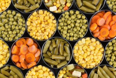 Group of open canned vegetables shot from a high angle. Assorted veggies carrots, corn, green beans, peas and mixed vegetables.